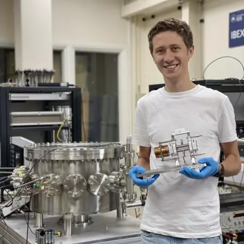 Jake Flowerdew, holding the previous IBEX Paul trap, stands next to the vacuum vessel containing the IBEX-2 trap in the IBEX lab at the Rutherford Appleton Laboratory.
